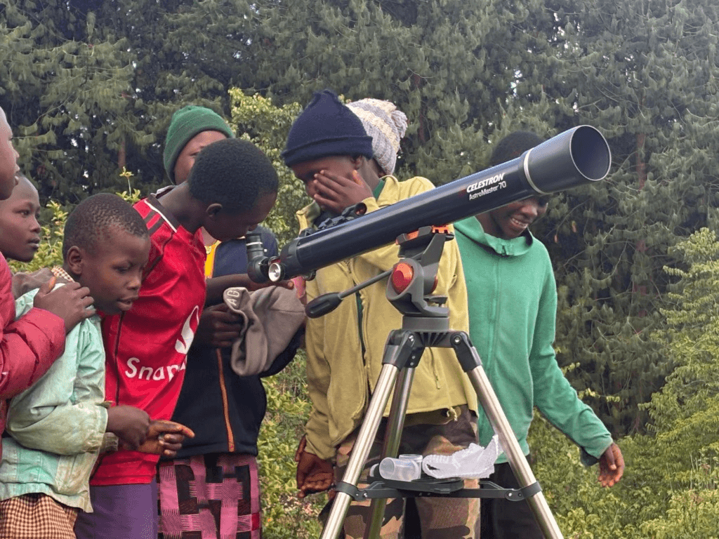 A group of excited local youth in Mt. Elgon taking turns looking through a ForbSpace telescope.